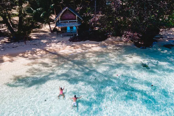 コワイ島トラットタイはコチャン近くのスニートロピカルアイランドです ビーチの木製竹小屋バンガロー タイの熱帯島で海で泳いでいる若い男女 — ストック写真
