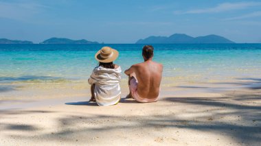 Koh Wai Adası Trat Tayland, Koh Chang yakınlarında teneke bir tropikal adadır. Tayland 'da lüks bir tatil sırasında tropik bir plajda oturan genç bir çift kadın ve erkek.