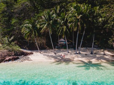Koh Wai Adası Trat Tayland, Koh Chang yakınlarında teneke bir tropikal adadır. Kumsaldaki ahşap bambu kulübesi. Tayland 'da tropikal bir adada palmiyeli bir çift genç adam ve kadın.