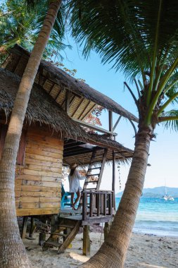 Koh Wai Adası Trat Tayland, Koh Chang yakınlarında teneke bir tropikal adadır. Kumsaldaki ahşap bambu kulübesi. Tayland 'da tropik bir adada genç bir çift kadın ve erkek.
