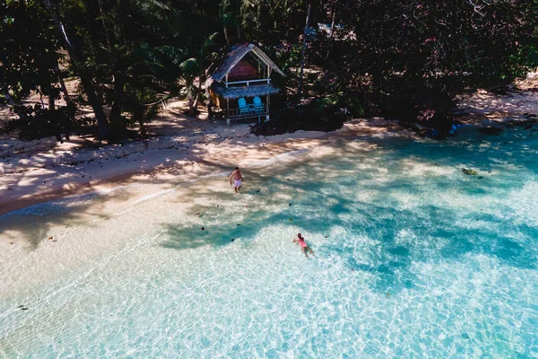 コワイ島タイはコチャン近くのスズニートロピカルアイランド ビーチの木製竹小屋バンガロー タイの熱帯島で青い海で泳いでいる若い男女 — ストック写真