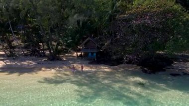 Koh Wai Adası Trat Tayland, Koh Chang yakınlarında teneke bir tropikal adadır. Kumsaldaki ahşap bambu kulübesi. Tayland 'da tropikal bir adada genç bir çift kadın ve erkek ve mavi bir okyanus.