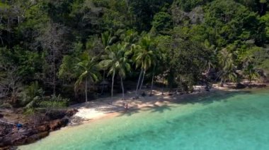 Koh Wai Adası Trat Tayland plajda ahşap bambu kulübesi, palmiye ağaçları ve turkuaz renkli bir okyanus. Koh Wai Adası 'ndaki tropik bir plajda genç bir çift ve kadın.
