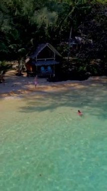 Koh Wai Adası Trat Tayland, Koh Chang yakınlarında. Kumsaldaki ahşap bambu kulübesi ve Tayland 'da bir tropikal adada tatil yapan genç bir çift kadın ve erkek.
