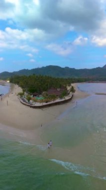 Birkaç erkek ve kadın Koh Muk sahilinde yürüyorlar. Palmiye ağaçları ve yumuşak beyaz kumları olan tropikal bir ada ve Trang Tayland 'da Koh Mook Andaman Denizi' nde turkuaz renkli bir okyanus.