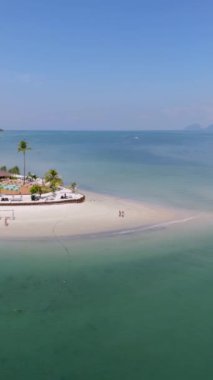 Koh Muk 'ta insansız hava aracı manzarası. Palmiye ağaçları, yumuşak beyaz kum ve turkuaz renkli bir okyanus, Koh Mook Trang Andaman Denizi Tayland, sahilde yürüyen birkaç erkek ve kadın.