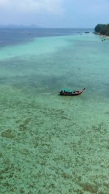 İnsansız hava aracı Koh Kradan 'da tropikal bir ada. Palmiye ağaçları, yumuşak beyaz kum ve turkuaz renkli bir okyanus. Koh Kradan Adası mercan kayalıklarında uzun kuyruklu tekneler.