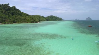 Koh Krada 'da mavi bir okyanusta kano süren genç bir adam ve Koh Kradan Trang Tayland' da turkuaz renkli bir okyanus.