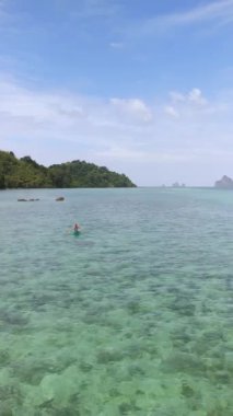 Koh Kradan Tayland 'da mavi bir okyanusta kano süren genç adamlar.