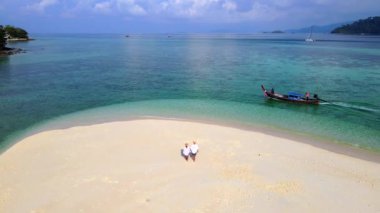 Güney Tayland 'da Koh Lipe Adası okyanusunda beyaz bir kumsalda yürüyen birkaç erkek ve kadın. Turkuaz renkli okyanus ve Ko Lipe' deki beyaz kumlu kumsalda..