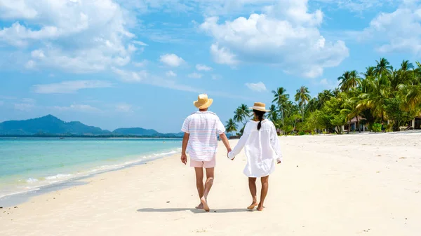 一对年轻的高加索男人和一个泰国亚洲女人在热带岛屿高目岛的海滩上散步 他们的棕榈树是柔软的白沙滩 而在泰国的高目岛则是一片草屋色的海洋 — 图库照片