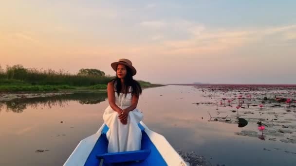 レッドロトスの海 ノン湖 ウドンタニ イサリアのレッドロータス湖で日の出にボートで帽子を持つアジアの女性 — ストック動画