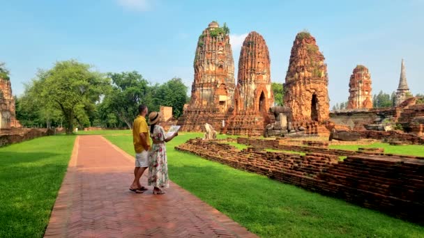 タイのワット マハッタットにあるアユタヤは 朝のタイのアユースタヤ遺跡に遺跡を残しています タイの古い寺院を見ている彼女の手の観光地図を持つ男性と女性のカップル — ストック動画