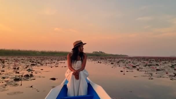 レッドロトスの海 ノン湖 ウドンタニ イサリアのレッドロータス湖で日の出にボートで帽子を持つアジアの女性 — ストック動画