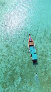Okyanusun gök mavisi sıvısında yüzen uzun kuyruklu bir tekne, sıvı genleşmeyle çevrili. Koh Krada, Tayland