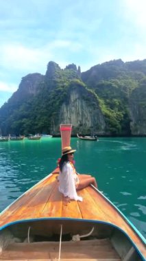 Kho Phi Tayland 'da uzun kuyruklu bir teknenin önünde Asyalı kadınlar.,