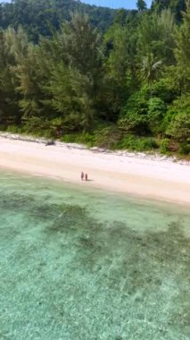 Koh Ngai sahilinde yürüyen bir çift palmiye ağaçları ve yumuşak beyaz kumu olan tropik bir ada ve Koh Ngai Krabi Tayland 'da turkuaz renkli bir okyanus.