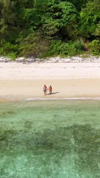 一对夫妇在海滩上散步 Drone从空中俯瞰着泰国Koh Ngai的一个热带岛屿 岛上有棕榈树和柔软的白沙 还有一个草屋色的海洋 — 图库视频影像