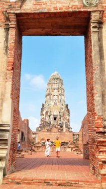 Bileşik yapı malzemelerinden yapılmış simetrik cepheli güzel bir tapınağın önünde fotoğraf için poz veren iki kişi. Gökyüzü Ayutthaya, Tayland sahnesine sanatsal katkı sağlıyor.