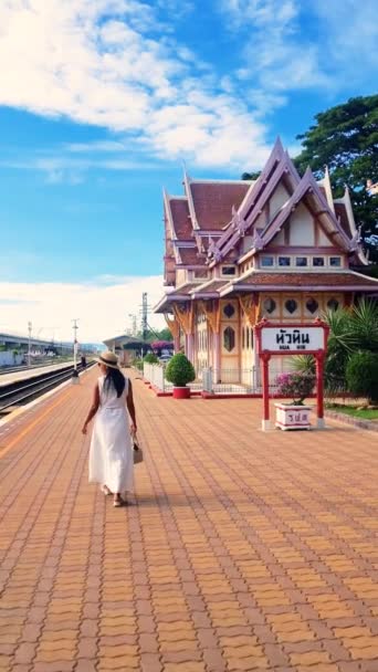 流れる白いドレスの女性が駅に向かって歩いていて 曇った空に向かってシルエット 風景は植物で点在し タイのホアヒン 平和な雰囲気を作り出しています — ストック動画