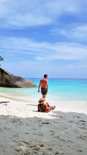 男と女が一緒にビーチを楽しんでいて 澄んだ空の下に輝く水を飲んでいる 風は穏やかで タイのシミラン諸島をリラックスした雰囲気を作り出しています — ストック動画
