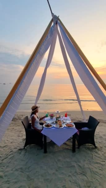 여자는 지평선 로맨틱 태국의 풍경으로 둘러싸인 해변에 테이블에 시간을 즐긴다 — 비디오