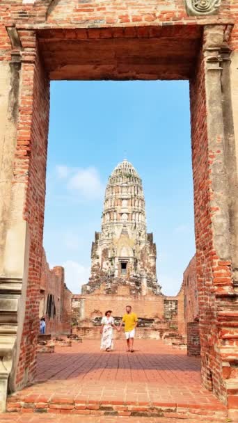 複合建築材料で作られた対称的な正面を持つ美しい寺院の前に写真を撮る2人の個人 空がタイのアユタヤのアーティストリーに加わる — ストック動画