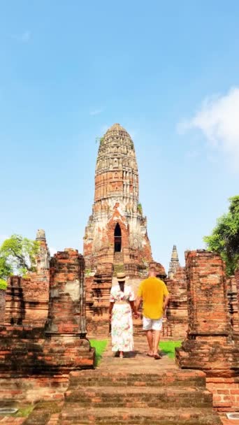 男性と女性は 古代の木々に囲まれた歴史的な寺院の階段を下り タイの旅行冒険アユタヤの間に神聖な場所の芸術と歴史を示しています — ストック動画