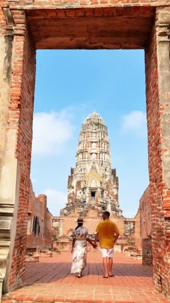 カップルは中世の寺院に向かってレンガのアーチを歩いていて タイの考古学的遺跡アユタヤで空に対する正面の対称性を賞賛しています — ストック動画