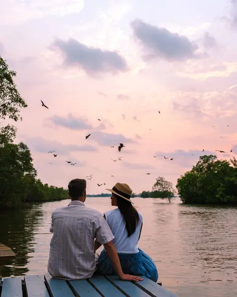 タイのチャンタブリのマングローブの日没で海のイーグル 赤い裏地の海の鷲 木製の桟橋で日没を見ている男性と女性のカップル 夏の旅行中にロマンチックな瞬間 — ストック写真