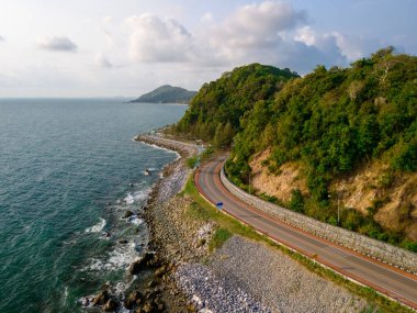 Tayland 'ın okyanus sahil yolu boyunca virajlı yolda giden araba. Yazın yol manzarası. Sahildeki otoyolda araba kullanmak çok güzel. Chantaburi Eyaleti Tayland, insansız hava aracı manzaralı