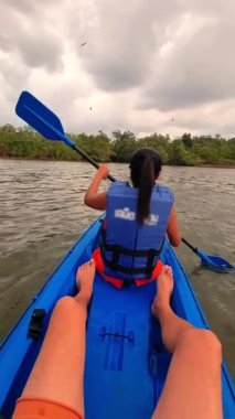 Tayland 'da nehirde kanoyla gezen Asyalı Taylandlı kadınlar gün batımında mangrov ormanında uçan deniz kartalları.