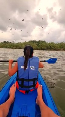 Tayland 'da nehirde kano süren Asyalı Taylandlı kadınlar ve etrafta uçan deniz kartalları.