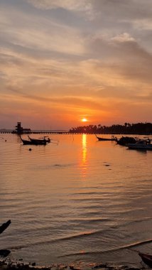 Zarif bir şekilde ışıldayan suda yüzen bir grup teknenin büyüleyici görüntüsü huzur ve maceranın mükemmel bir resmini oluşturuyor. Koh Mook Tayland 