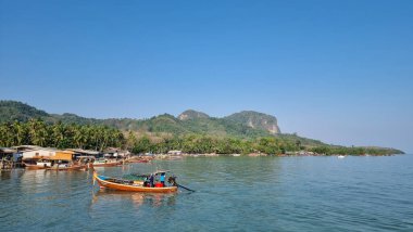 Koh Mook Tayland 20 Ocak 2024, sakin bir okyanusun sakin sularında yüzen küçük bir tekne, yukarıdaki berrak mavi gökyüzünü yansıtıyor.. 