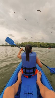 Bir erkek ve bir kadın, sakin bir gölde birlikte kano çekiyorlar. Huzurlu doğayla çevrili. Chantaburi Tayland 