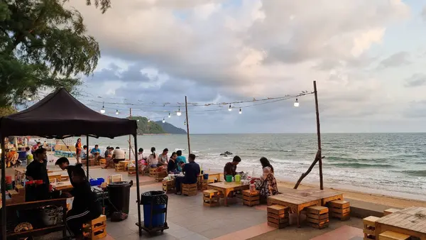 Chantaburi Tayland 15 Mart 2024 'te geniş okyanusun kıyısındaki kumlu bir plajda duran çeşitli bireyler, merak ve birlik hissiyle ufka bakıyorlar..