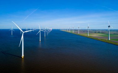 Hollanda Flevoland 'da geniş bir su kütlesi, rüzgarın esintili bir bahar gününde zarif bir şekilde yakaladığı çok sayıda yel değirmeniyle benekli. Değirmen türbinleri