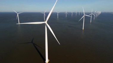 Okyanustaki yel değirmeni parkı, Hollanda 'da bahar mevsiminde güneşli bir günde yeşil enerji üreten yel değirmeni türbinlerinin insansız hava görüntüsü.