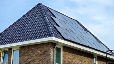 Çatıda güneş panelleri olan yeni yapılmış evler güneşli bir gökyüzüne karşı, siyah güneş panelleri olan yeni binalar. Zonnepanelen, Zonne Energie, Çeviri: Güneş Paneli, Güneş Enerjisi
