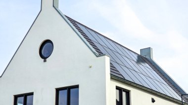 Çatıdaki siyah güneş panelleri güneşli bir gökyüzüne karşı siyah güneş panelleri olan modern bir eve yakın. Zonnepanelen, Zonne Energie, Çeviri: Güneş Paneli, Güneş Enerjisi