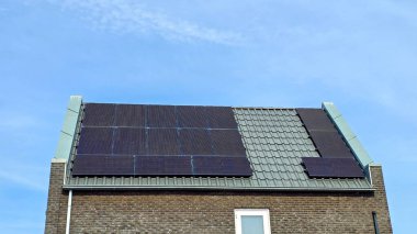 Çatı üzerinde siyah güneş panelleri olan modern aile evleri güneşli bir gökyüzüne karşı siyah güneş panelleri olan yeni binaları kapatıyorlar. Zonnepanelen, Zonne Energie, Çeviri: Güneş Paneli, Güneş Enerjisi