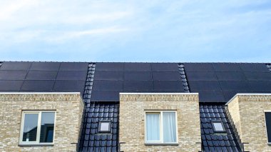 Çatıda siyah güneş panelleri olan Hollandalı aile evi güneşli bir gökyüzüne karşı siyah güneş panelleri olan yeni binayı kapatıyor. Zonnepanelen, Zonne Energie, Çeviri: Güneş Paneli, Güneş Enerjisi