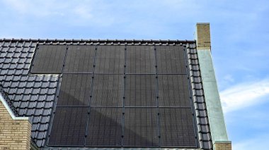 Çatıda siyah güneş panelleri olan Hollanda Suburban bölgesi güneşli bir gökyüzüne karşı siyah güneş panelleri olan yeni evi kapatın. Zonnepanelen, Zonne Energie, Çeviri: Güneş Paneli, Güneş Enerjisi