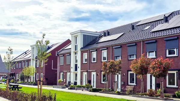 Newly built houses with black solar panels on the roof against a sunny sky, Zonnepanelen, Zonne energie, Translation: Solar panel, Sun Energy