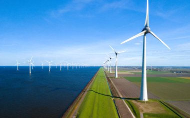 Kıyıdaki yel değirmeni parkı ve mavi gökyüzü, okyanustaki yel değirmeni parkı. Hollanda Avrupa 'sı. Noordoostpolder Flevoland 'daki yel değirmeni türbinleri Hollandalı bir hendekte
