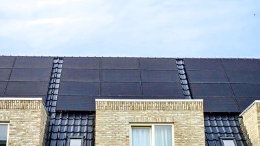 Baharda çatıda siyah güneş panelleri olan yeni yapılmış evler, siyah güneş panelleri olan yeni binaların kapatılması. Zonnepanelen, Zonne Energie, Çeviri: Güneş Paneli, Güneş Enerjisi