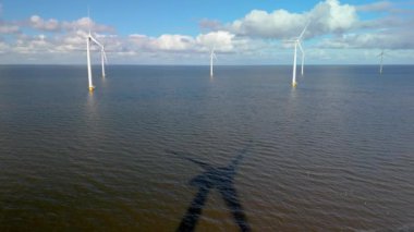 Baharda Hollanda 'daki yel değirmeni parkı okyanustaki yel değirmeni türbinlerinin insansız hava görüntüsü elektrik üreten yeşil enerji üretiyor.
