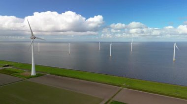 İlkbaharda Hollanda 'daki yel değirmeni parkı, elektrikli olarak yeşil enerji üreten yel değirmeni türbinlerinin insansız hava görüntüsü, Avrupa' da enerji geçişi, okyanusta ve karada rüzgar değirmenleri.