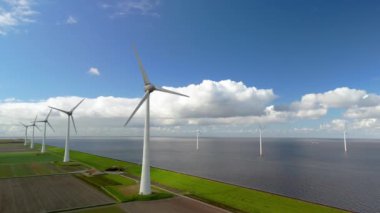 Baharda Hollanda 'daki yel değirmeni parkı, rüzgar türbinlerinin hava görüntüsü elektrik üreten yeşil enerji, kıyıda ve kıyıda dev yel değirmeni türbinleri, enerji geçişi.